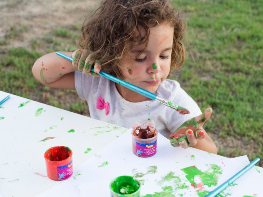 Niña jugando y pintando sus manos